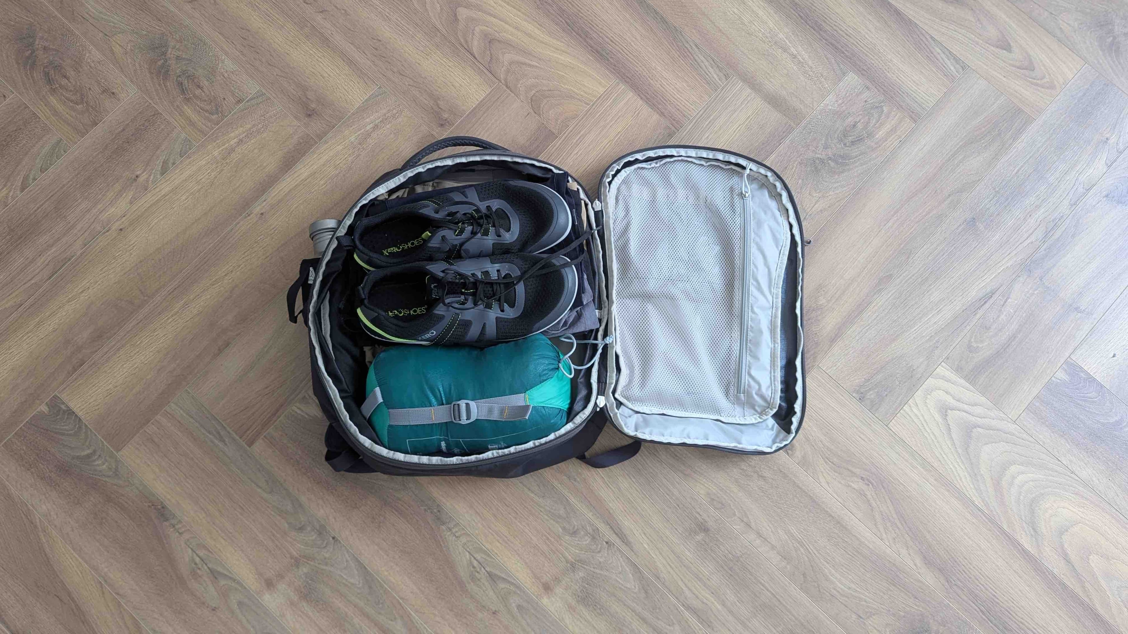 Interior of the Osprey Daylite 26+6L backpack open in clamshell mode, with shoes and a sleeping bag packed inside
